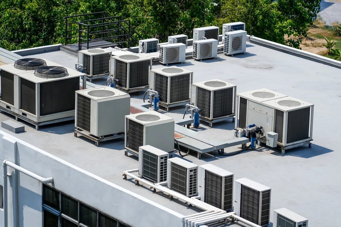 Rows of commercial rooftop HVAC condenser units on a large flat roof